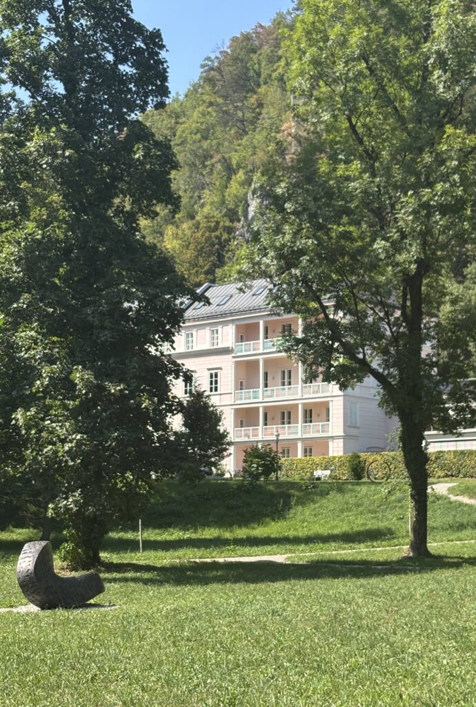 Arenberg Schloss - a 16th century palace with a pastel pink facade surrounded by manicured gardens and a sculpture park in Salzburg.