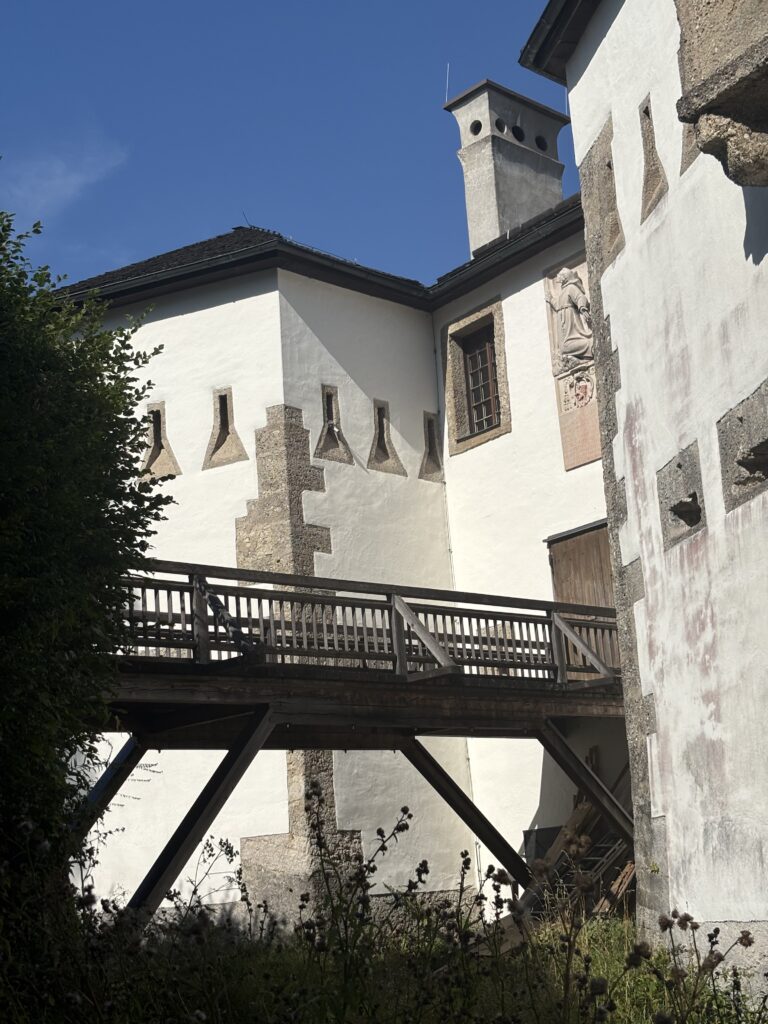 A close up on the Capuchin Monastery - featuring a wooden bridge and a whitewashed building made of stone featuring eyelet windows and square chimney.