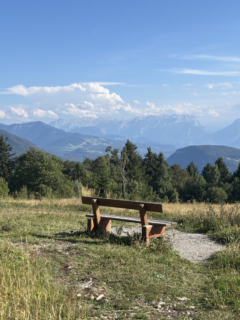 A bench in a big valley meadow called Zistelrundweg with the perfect viewpoint to the neighbouring mountain ranges of Gaisberg and Untersberg.