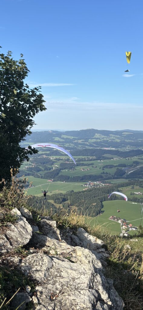 Gaisberg Peak - The Northern Takeoff point for paragliding. There are three paragliders descending into the green valley below.